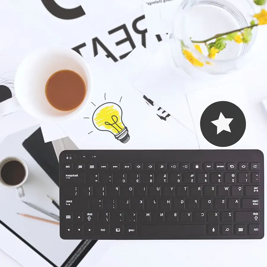 looking down on desktop with keyboard, coffee, writing utensils.